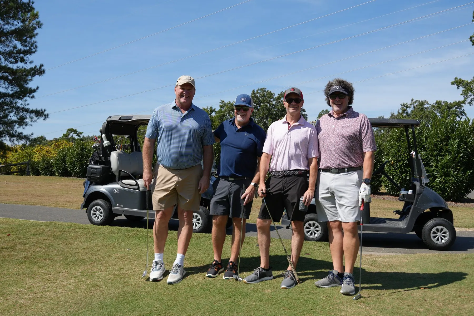 A four-player team standing beside their cart at the Capital City Golf Classic.