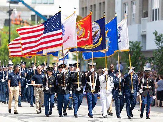 U.S. Armed Forces color guard marching with service flags during a military ceremony, representing all branches of the military